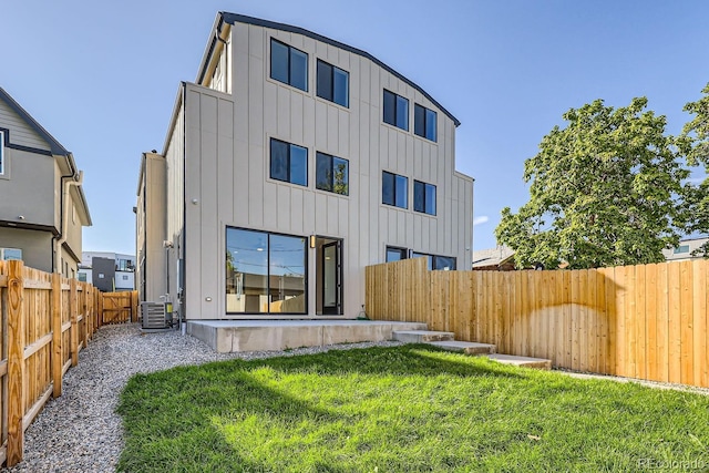 rear view of house with central air condition unit, a lawn, and a patio