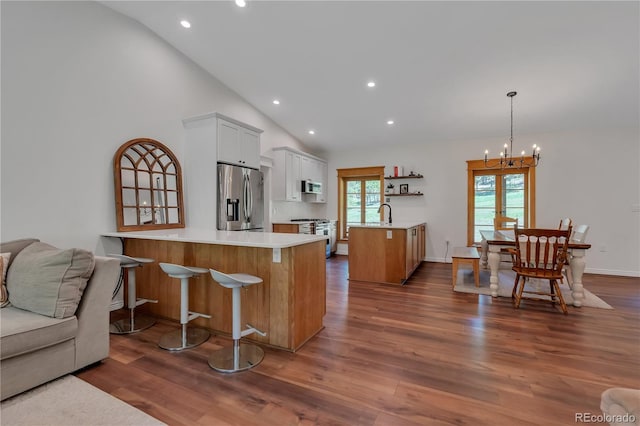 19745 Hopi Pines Grv, Peyton, CO 80831 - kitchen with appliances with stainless steel finishes, a peninsula, a chandelier, open floor plan, and a kitchen bar