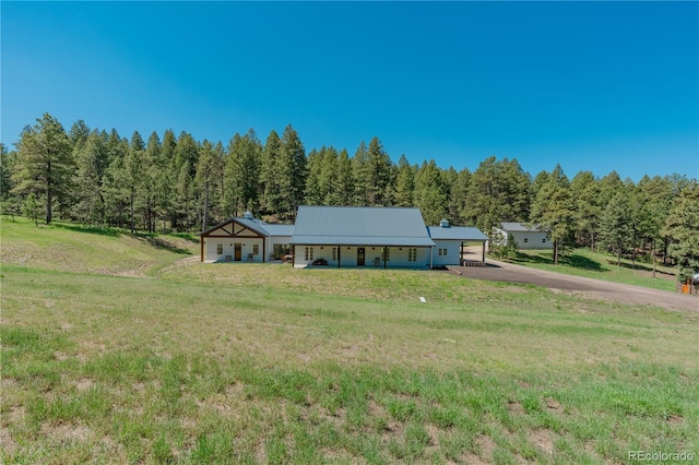 19745 Hopi Pines Grv, Peyton, CO 80831 - single story home with a front yard, asphalt driveway, a forest view, and covered porch