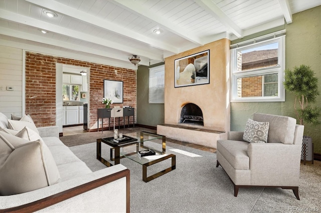 carpeted living room with a large fireplace, a wealth of natural light, and beamed ceiling