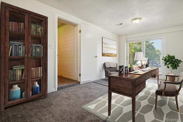 carpeted office space featuring a textured ceiling