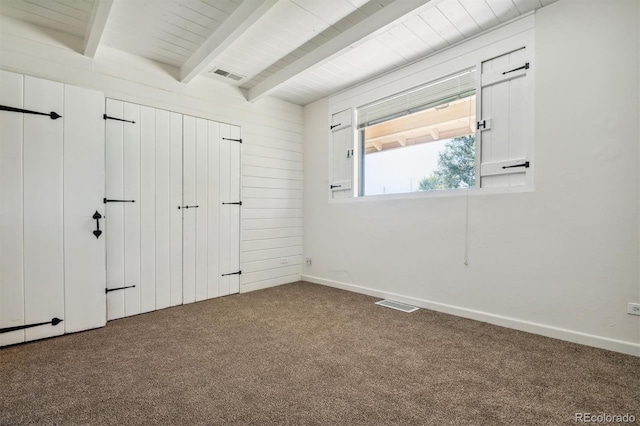 spare room with carpet flooring and beamed ceiling