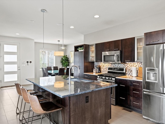 3368 Cranston Cir, Highlands Ranch, CO 80126 - kitchen featuring stainless steel appliances, a breakfast bar area, decorative backsplash, dark brown cabinets, and a kitchen island with sink
