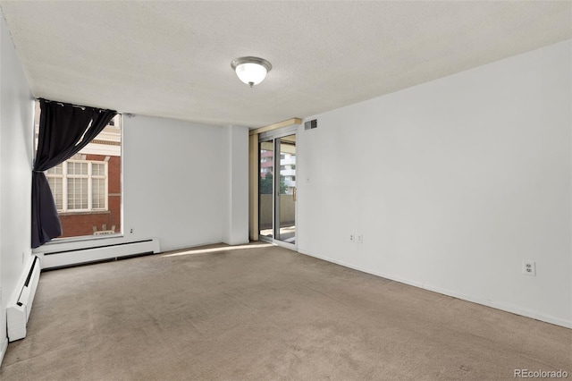 carpeted empty room with baseboard heating and a textured ceiling