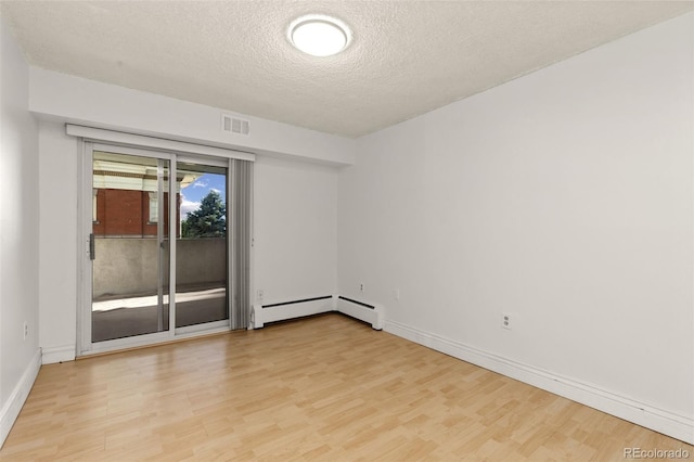 empty room with light hardwood / wood-style floors, a textured ceiling, and baseboard heating