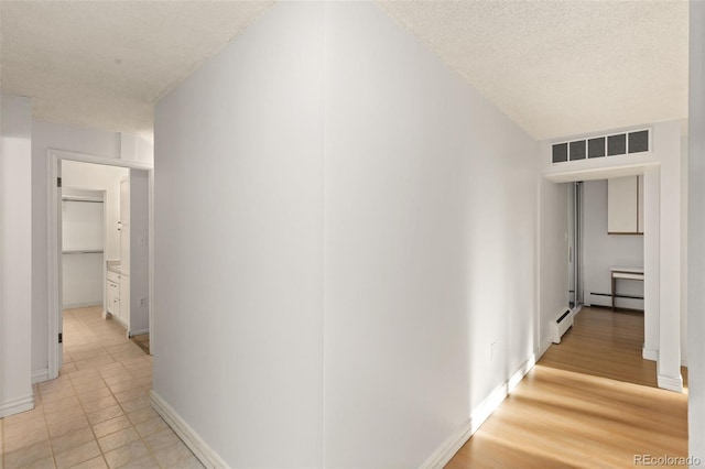 hallway with baseboard heating and a textured ceiling