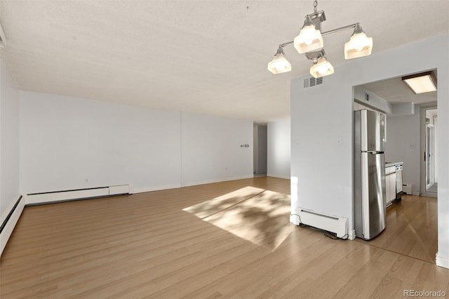 empty room with hardwood / wood-style floors, a textured ceiling, and baseboard heating