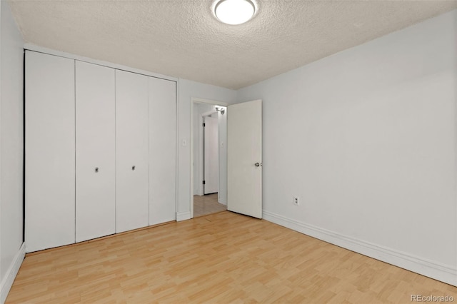 unfurnished bedroom with a closet, light hardwood / wood-style flooring, and a textured ceiling