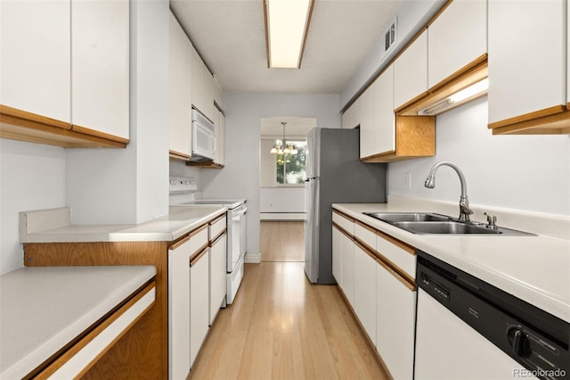 kitchen with white appliances, a baseboard heating unit, sink, and white cabinets