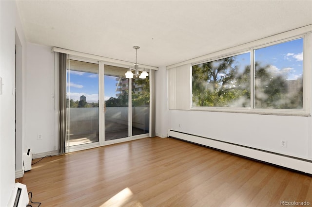 unfurnished dining area featuring a baseboard radiator, a baseboard heating unit, expansive windows, wood finished floors, and a chandelier