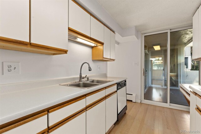 kitchen featuring white cabinets, a baseboard radiator, light wood-style flooring, light countertops, and a sink