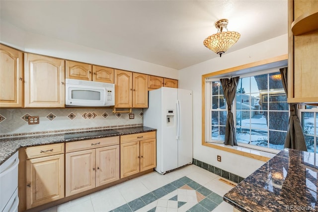 kitchen featuring white appliances, light tile patterned floors, dark stone counters, and tasteful backsplash