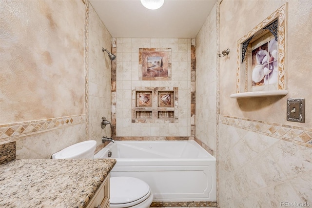 full bathroom with toilet, tiled shower / bath, vanity, and tile walls