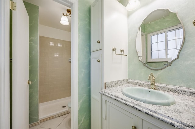 bathroom with tiled shower, vanity, toilet, and tile patterned flooring