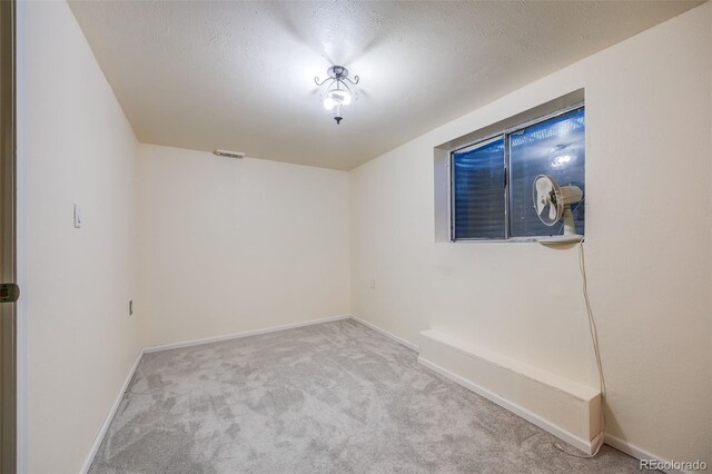 unfurnished room with light colored carpet and a textured ceiling