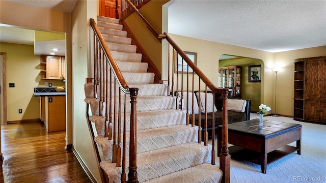 16639 E Berry Ln, Centennial, CO 80015 - stairs featuring a textured ceiling, arched walkways, and wood finished floors