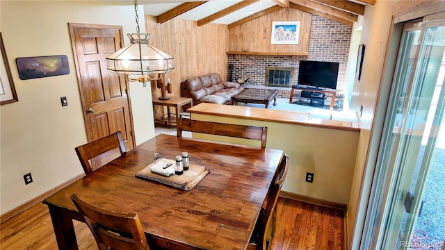 16639 E Berry Ln, Centennial, CO 80015 - dining area featuring wood finished floors, a chandelier, a brick fireplace, and wooden walls