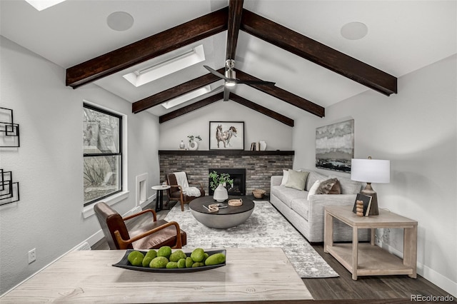 living room with vaulted ceiling with skylight, wood finished floors, ceiling fan, a fireplace, and baseboards