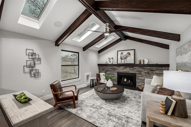 living room with wood finished floors, a ceiling fan, lofted ceiling with skylight, baseboards, and a fireplace