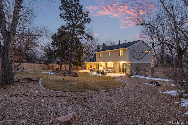 11861 E Yale Ct, Aurora, CO 80014 - back of house at dusk featuring a fenced backyard, brick siding, and a patio