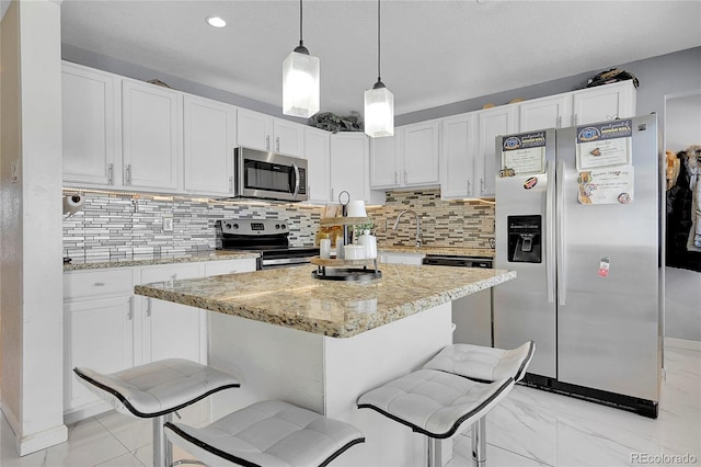 kitchen featuring appliances with stainless steel finishes, a breakfast bar area, pendant lighting, and white cabinets