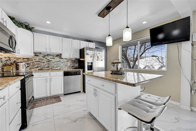 kitchen with stainless steel appliances, sink, a kitchen island, and white cabinets