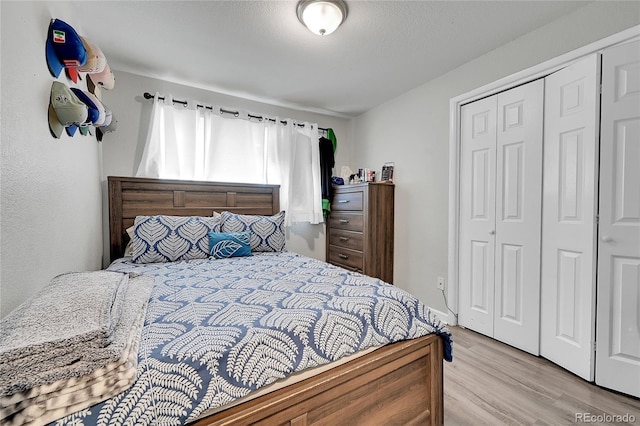 bedroom with a closet, a textured ceiling, and light wood-type flooring