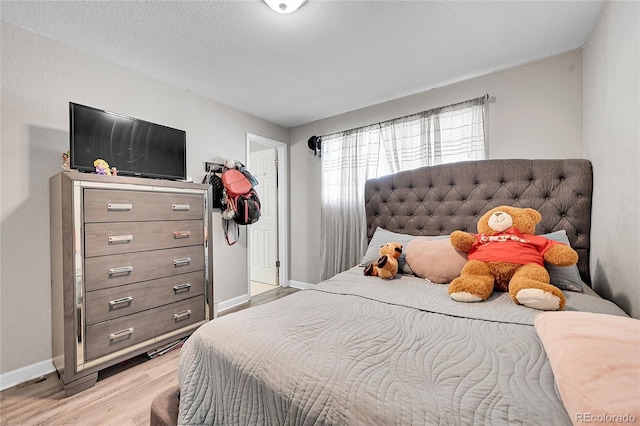 bedroom with a textured ceiling and light hardwood / wood-style flooring