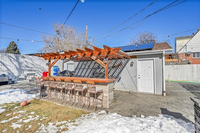 snow covered patio featuring a pergola and exterior bar