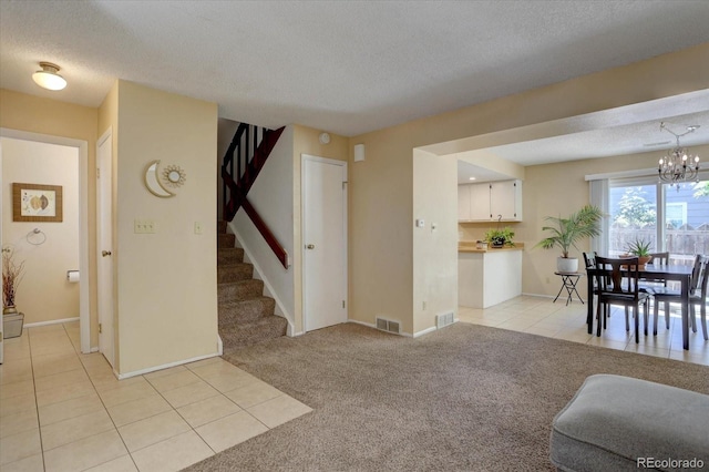 562 W Crestline Cir Unit 7D, Littleton, CO 80120 - living room featuring a textured ceiling, light tile patterned floors, stairs, light colored carpet, and a chandelier