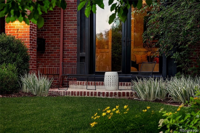 doorway to property with a lawn and brick siding