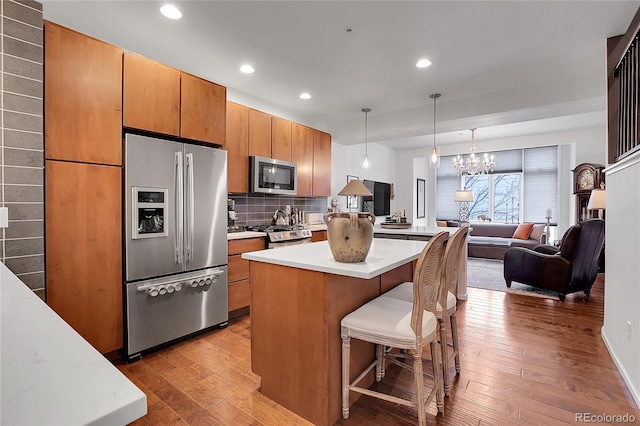 kitchen with a center island, stainless steel appliances, tasteful backsplash, decorative light fixtures, and a kitchen bar