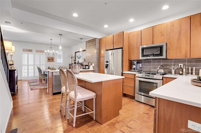 kitchen featuring a center island, stainless steel appliances, backsplash, a chandelier, and decorative light fixtures