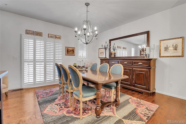 dining space with hardwood / wood-style floors and an inviting chandelier