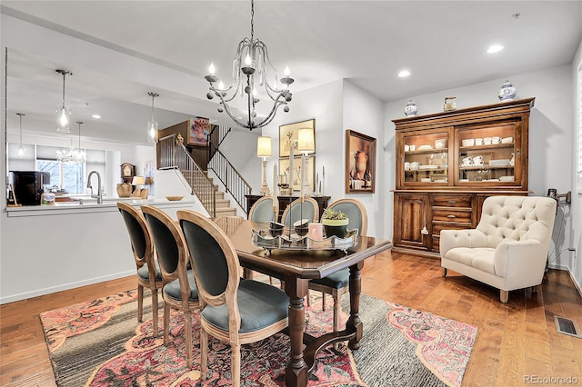 dining area with light wood-type flooring, a notable chandelier, and sink