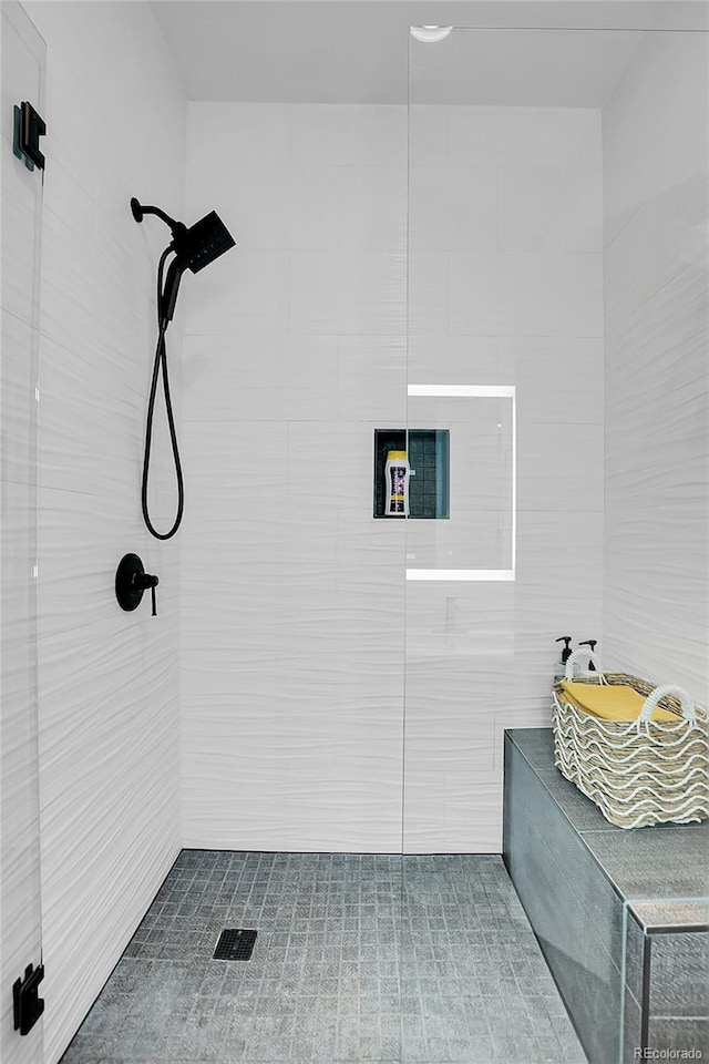 bathroom with a tile shower and tile walls