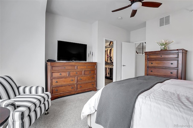 carpeted bedroom with ceiling fan, a spacious closet, and a closet