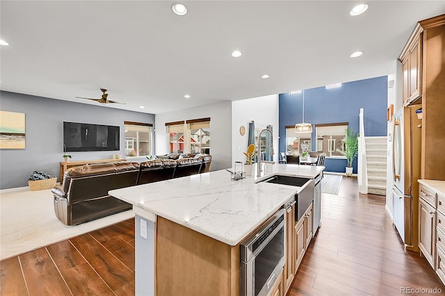 kitchen with dark wood-style floors, open floor plan, and a kitchen island with sink