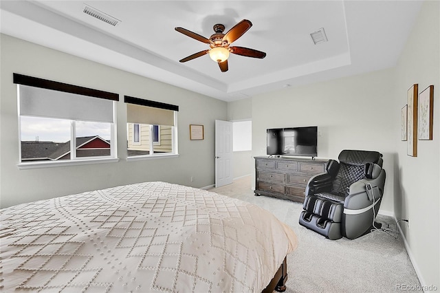 bedroom with light colored carpet, a tray ceiling, and visible vents