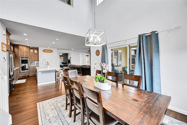 dining space featuring dark wood-style floors, a high ceiling, and recessed lighting