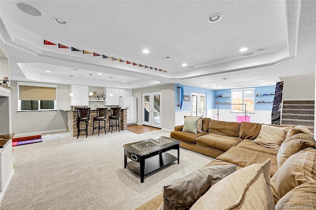 living area featuring a tray ceiling, indoor bar, stairway, and a textured ceiling