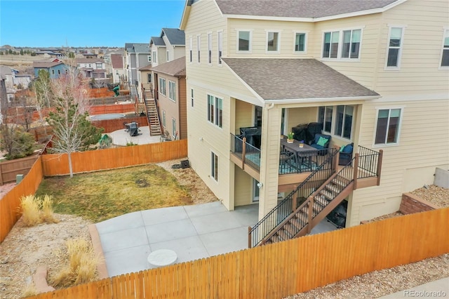 rear view of house featuring a fenced backyard, stairs, roof with shingles, and a patio