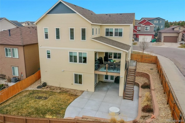 rear view of property featuring a lawn, a patio, a fenced backyard, stairs, and central AC