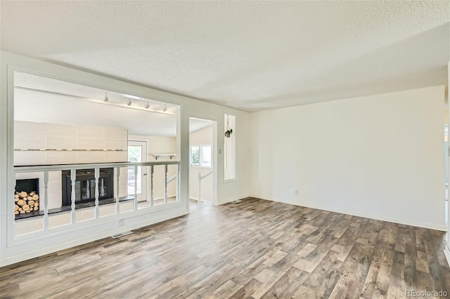 unfurnished living room featuring hardwood / wood-style flooring and a textured ceiling