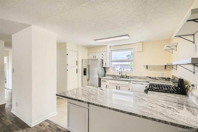 kitchen featuring sink, white cabinetry, stone counters, light hardwood / wood-style flooring, and appliances with stainless steel finishes