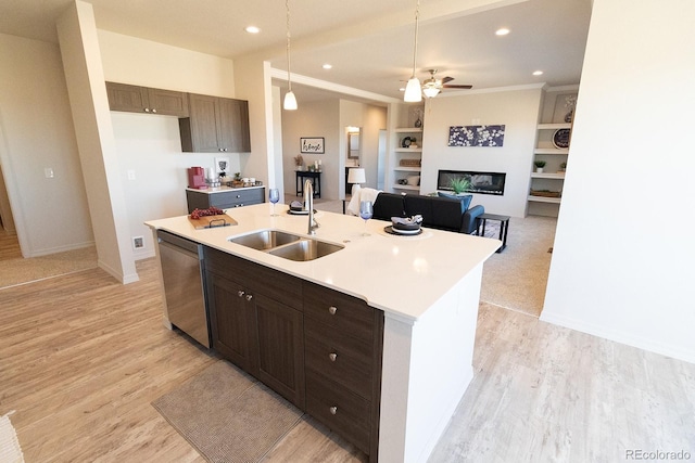 kitchen featuring a kitchen island with sink, sink, stainless steel dishwasher, built in shelves, and light hardwood / wood-style floors