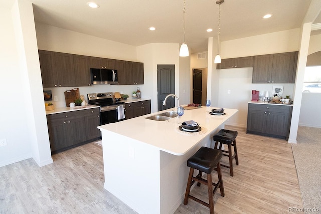 kitchen featuring appliances with stainless steel finishes, a breakfast bar, sink, pendant lighting, and a center island with sink