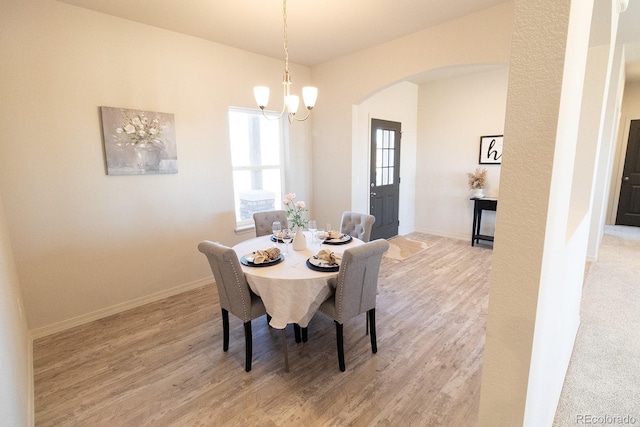 dining area with light wood-type flooring and an inviting chandelier