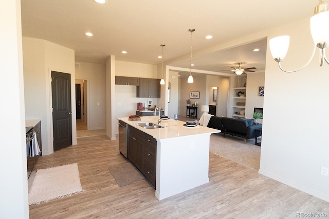 kitchen featuring dark brown cabinetry, ceiling fan, sink, built in features, and an island with sink