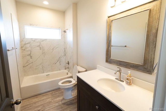 full bathroom featuring hardwood / wood-style floors, vanity, tiled shower / bath combo, and toilet